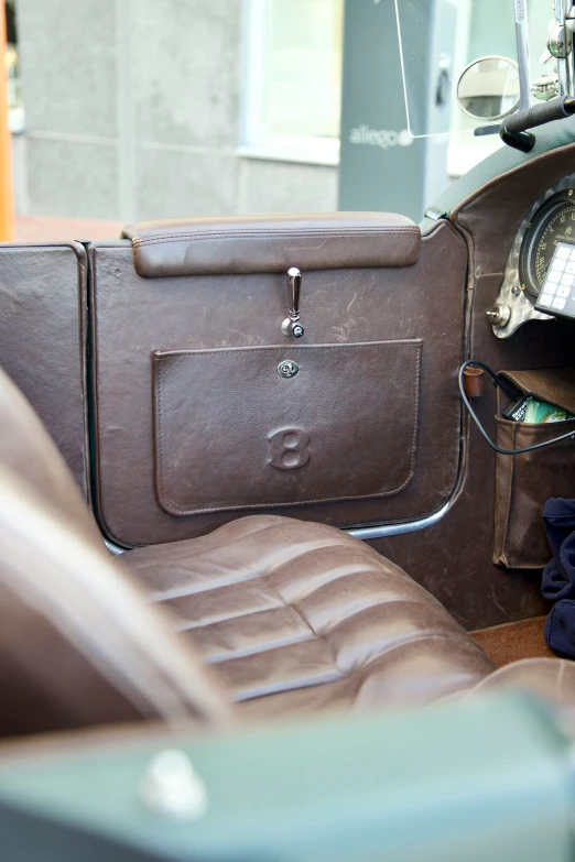 a leather suitcase in front of an old car