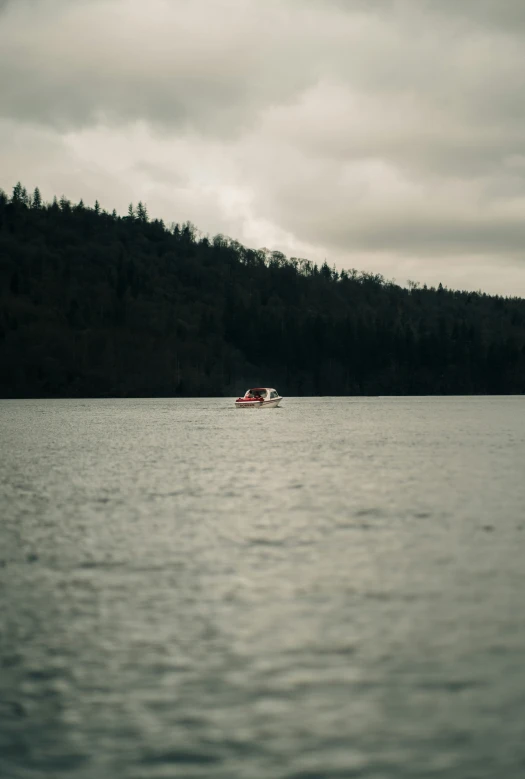 the boat is in the lake next to the forest