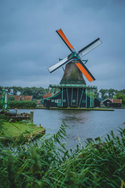 several large windmills near the river under a cloudy sky