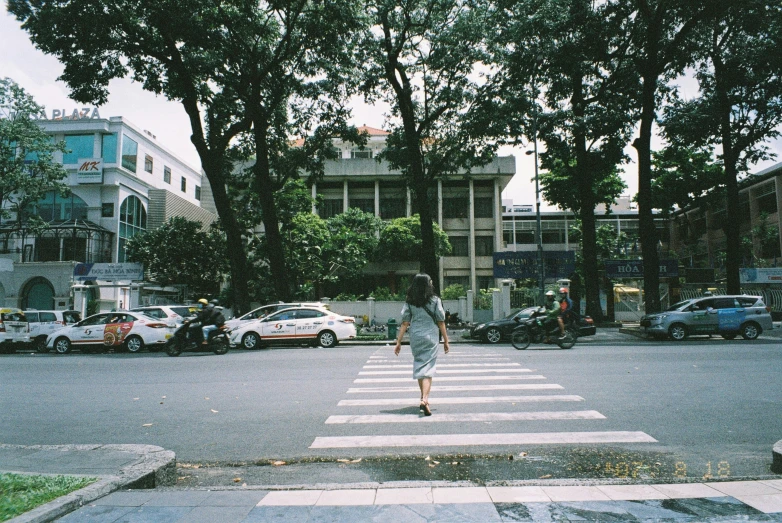 a person walking across a cross walk in front of a bunch of parked cars