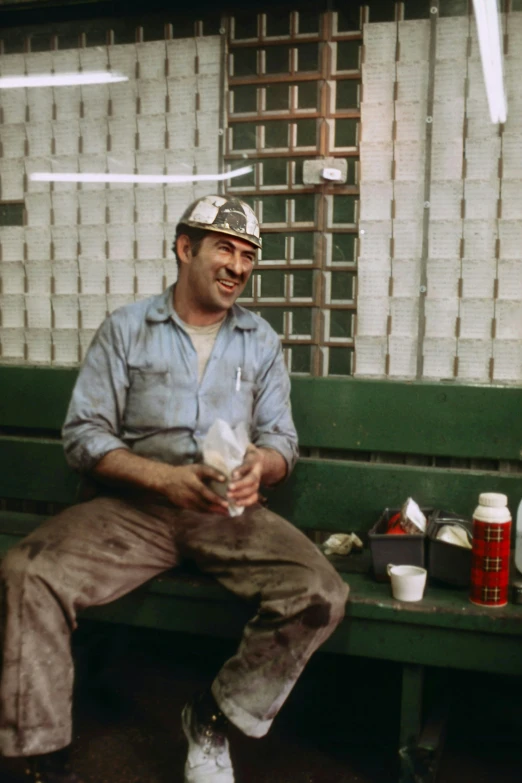 man smiling with drink and food on bench