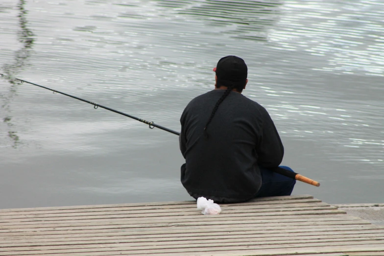 a man is sitting and fishing while holding his rod