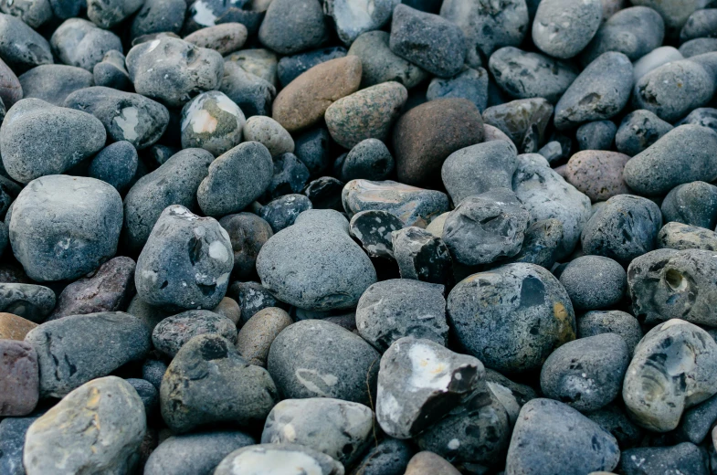 many stones, one in grey and one in black, are laying together