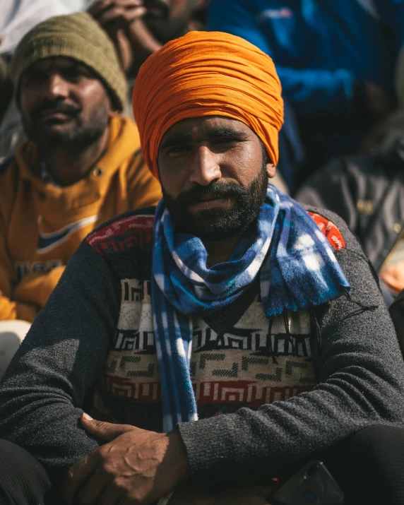 a man with an orange turban sits with other men