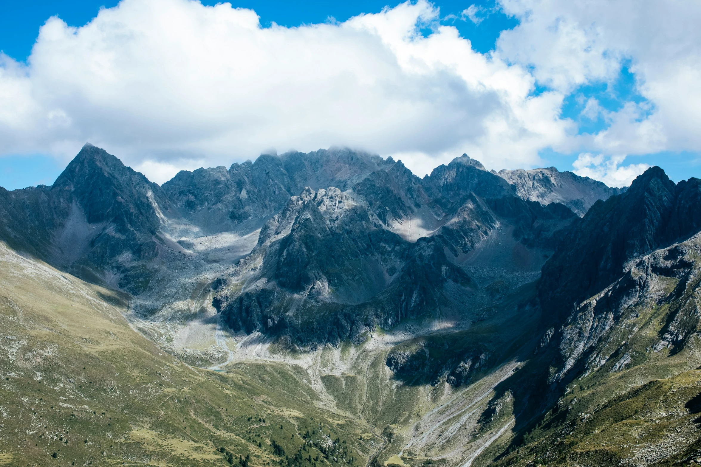 a mountain range with clouds overhead and green trees