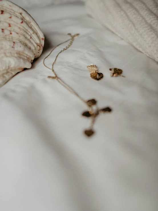 a sea shell and some earrings laying on a bed