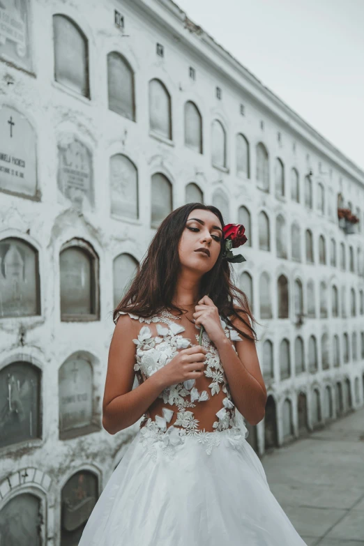 a woman wearing a wedding dress posing for a po outside