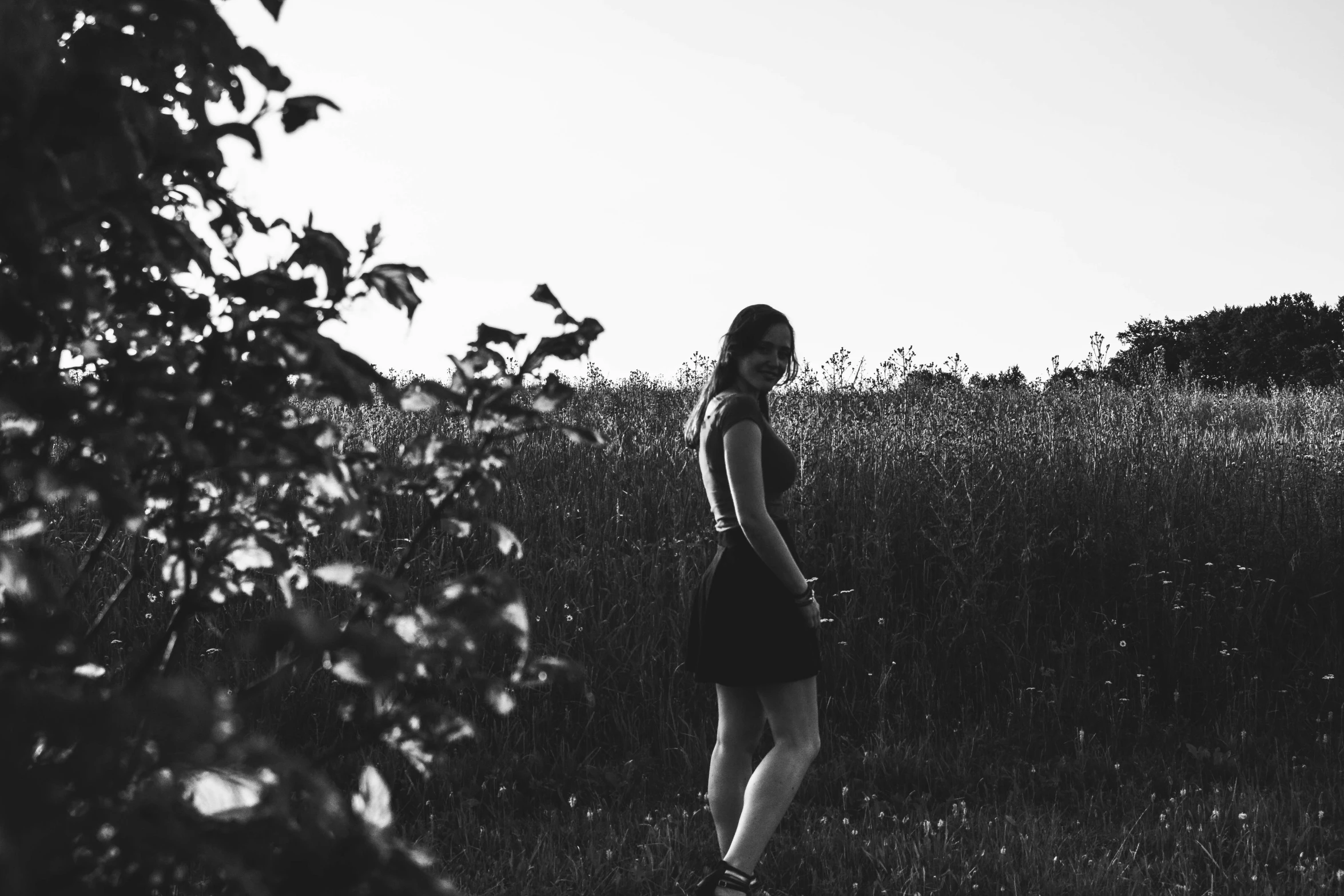 a woman in black is walking through a field