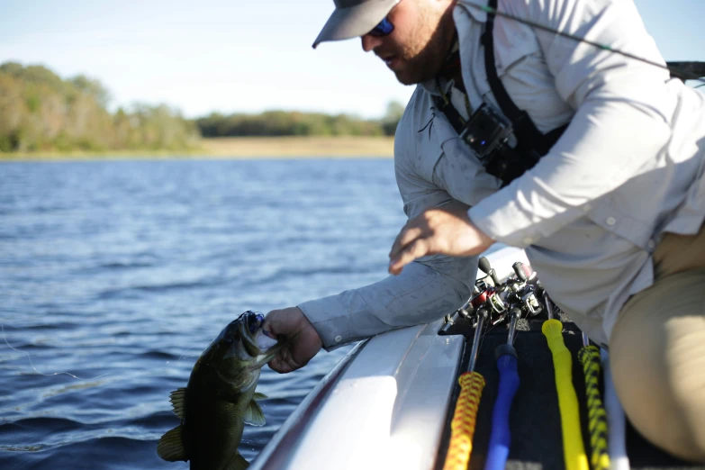 a man kneeling on a boat and looking at a fish