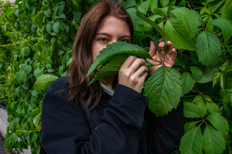 there is a woman standing in front of the leaves