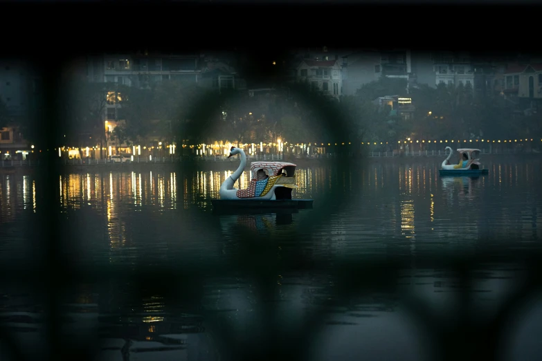 a couple of boats sailing on top of a lake at night