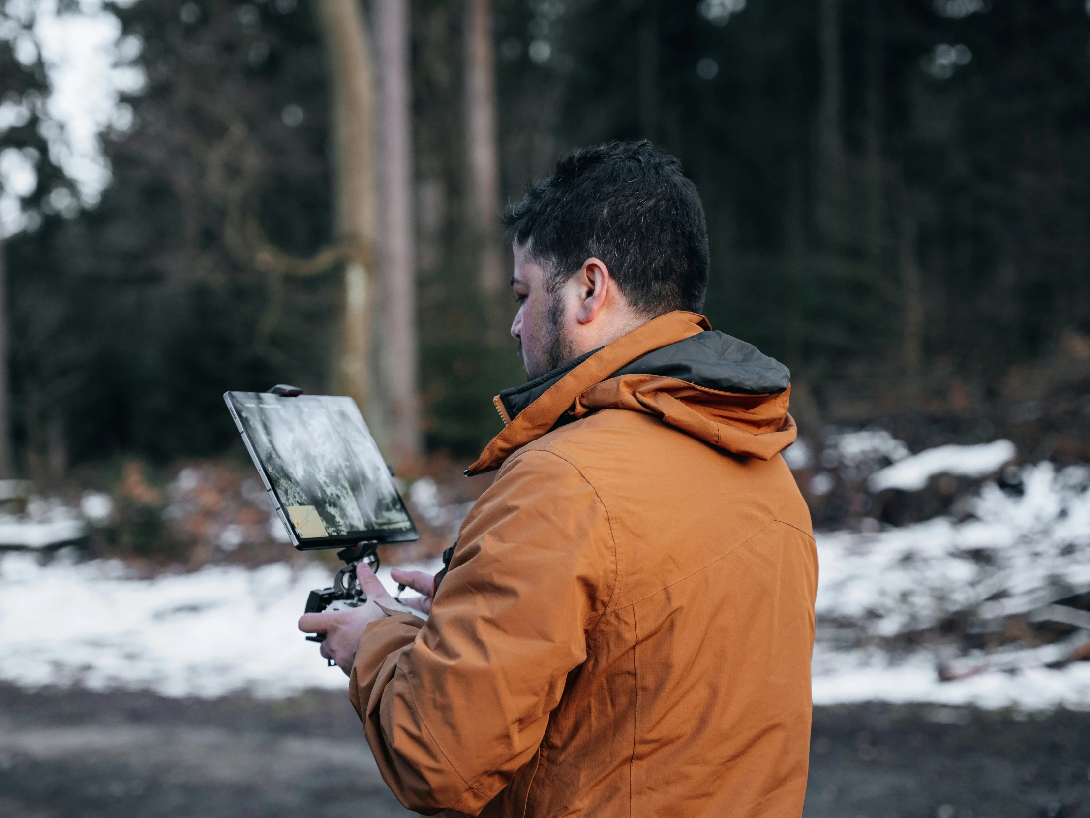 a man in an orange coat holds a laptop in his hands