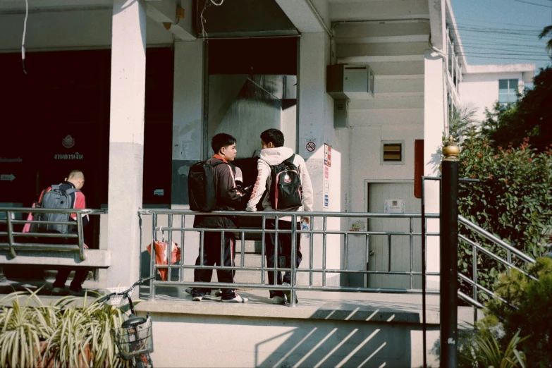 three children stand on a balcony of an apartment building