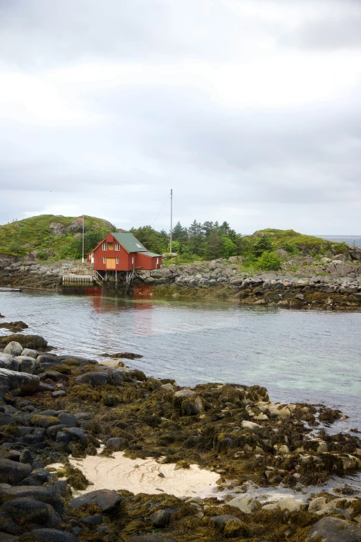 a house sitting on a beach near some water