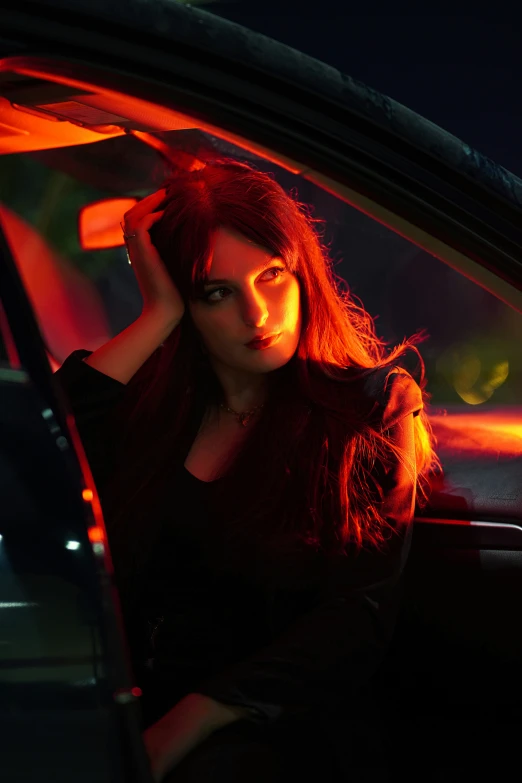a woman with red hair sitting inside of a car at night