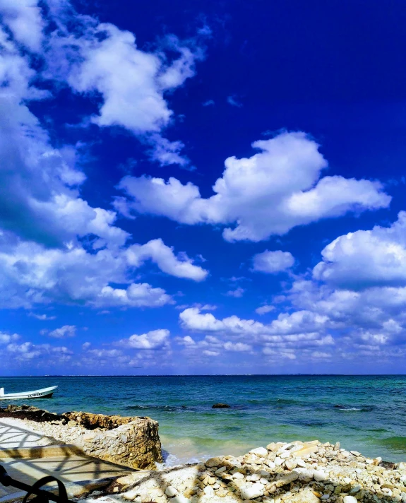 a boat sailing on the ocean by a rocky coastline