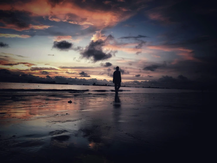 man standing on the beach watching a beautiful sunset
