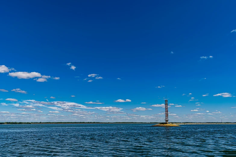 a boat sails in the open water beneath a partly cloudy sky