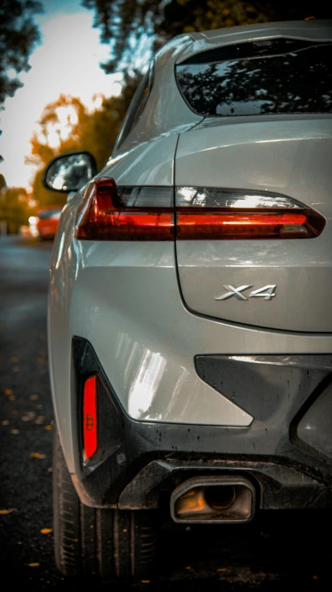 a gray car with its lights on sitting in a parking lot