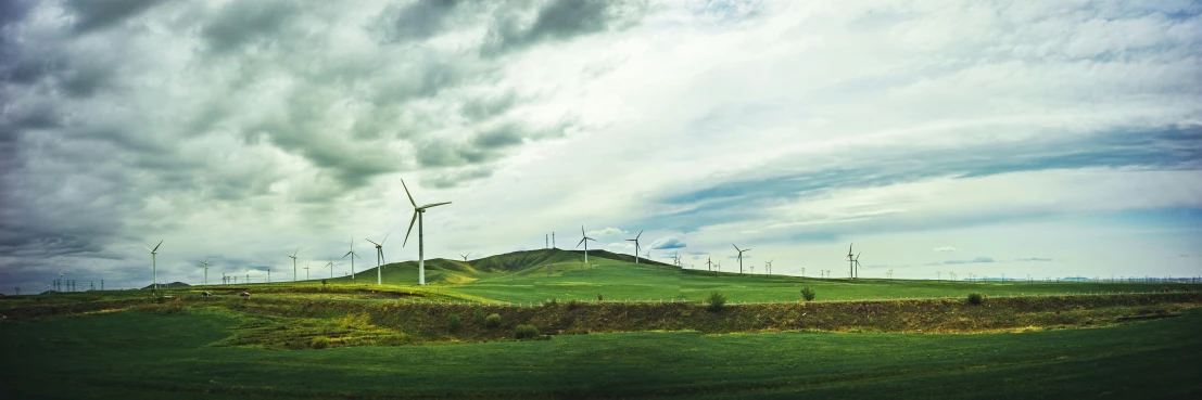 wind mills are in the distance against a cloudy sky