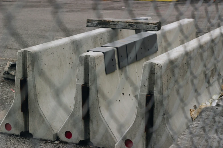 cement blocks on side of road surrounded by chain link fence
