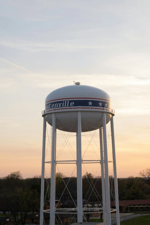 a water tower sits on the side of a parking lot