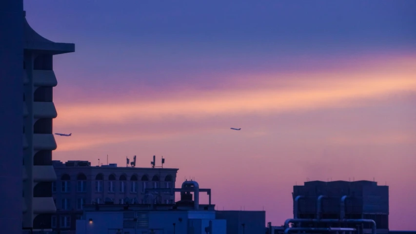 plane in flight in distance over buildings on a cloudy day