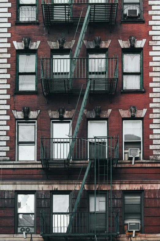 the building has fire escapes, a bench, and several windows on each floor