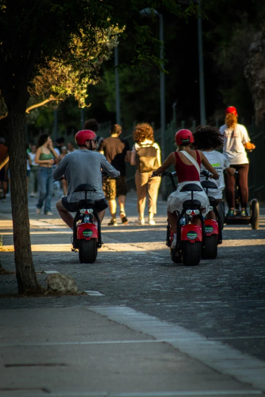 a group of people riding scooters down the street