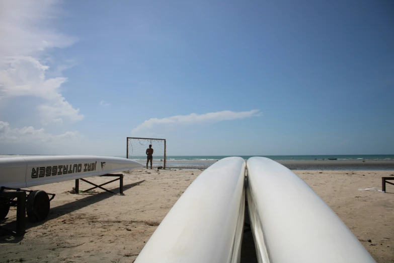 surfboards sitting on the sand of a beach with people in the background