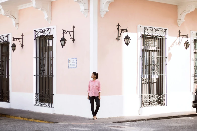 a woman standing outside of a pink building