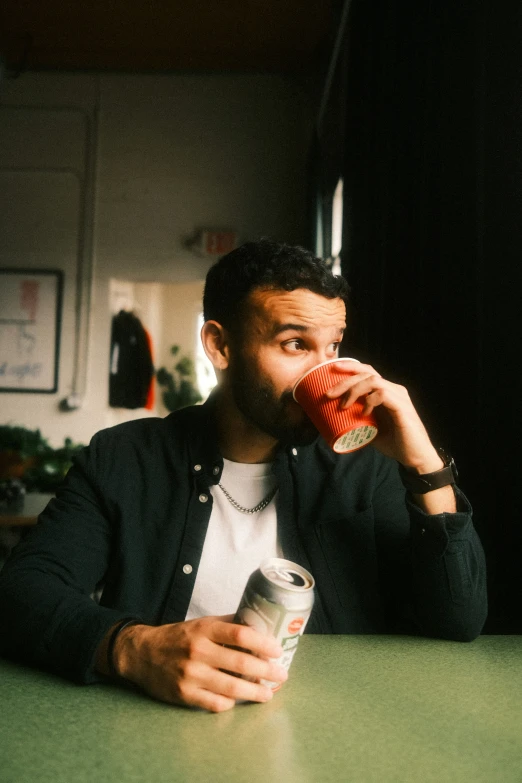 a man sitting at a table drinking a drink