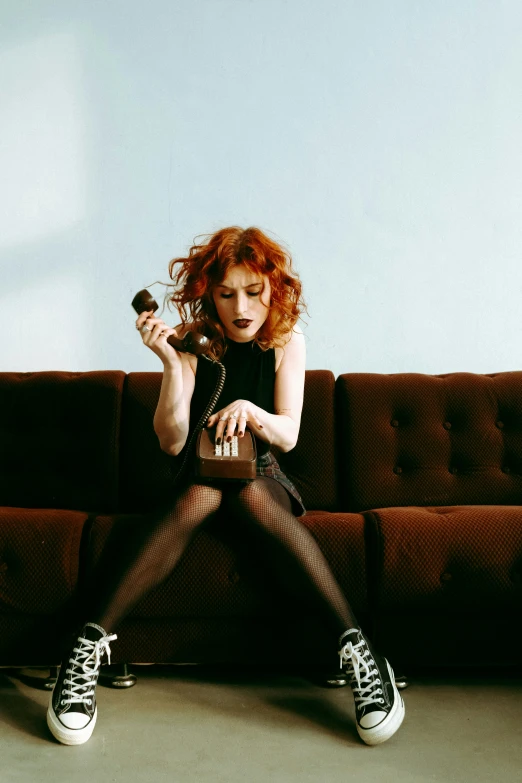 a beautiful woman sitting on top of a couch holding an object