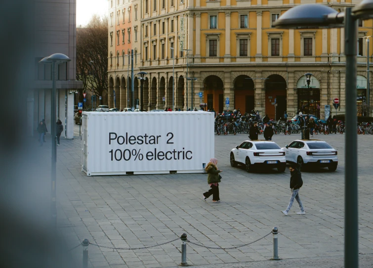 people walking around outside while a large sign shows the direction