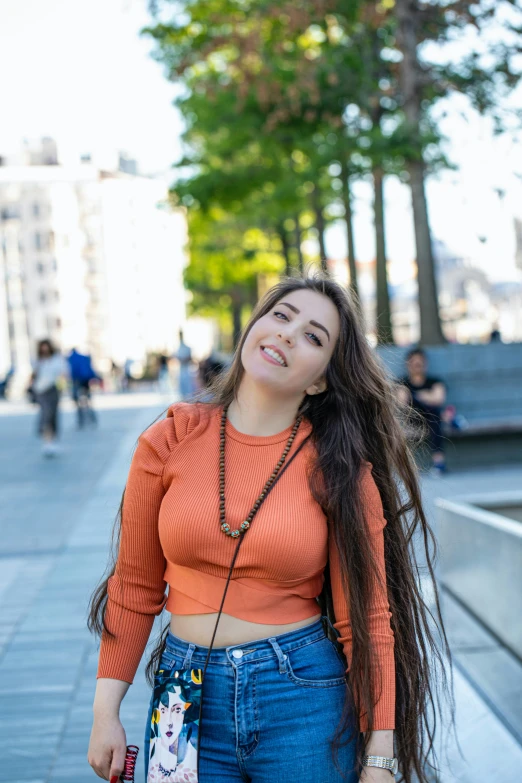 a girl standing in the street smiling with her hair in the wind