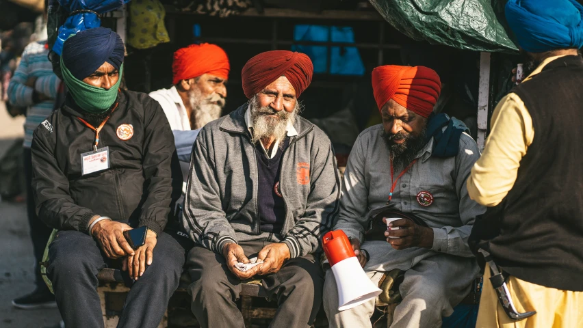 group of men wearing turbans sitting on park bench