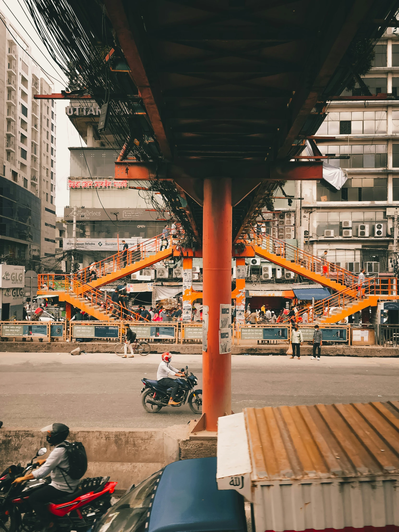 motorcycles parked under an orange colored structure on the street