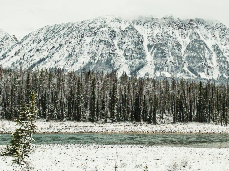 a snowy mountain with a small river running underneath it