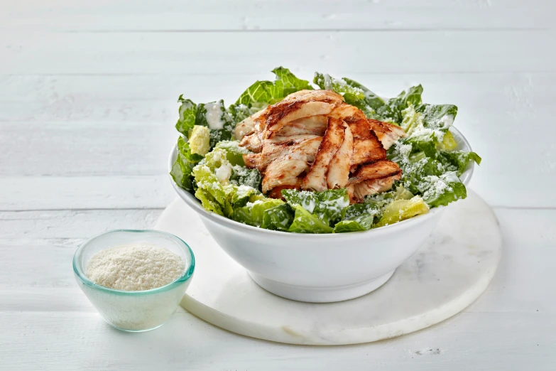 a white plate holding salad with chicken and lettuce