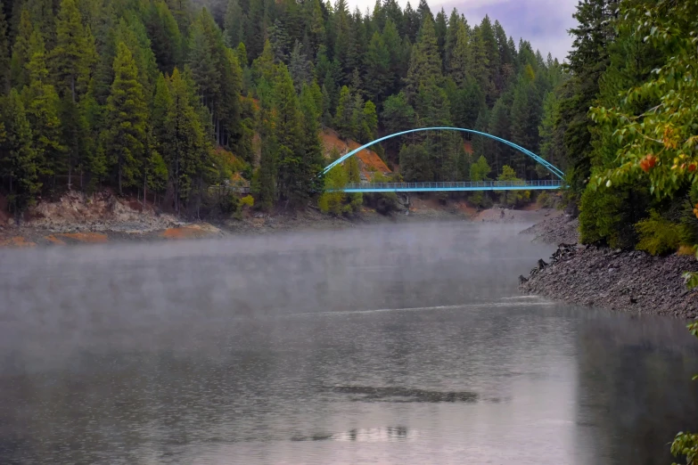 a bridge over a river covered in fog
