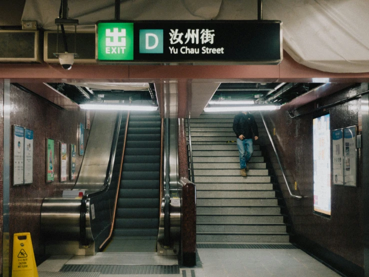 a man is sitting on the stairs in a subway