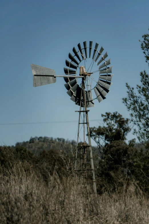 an old windmill leaning over in the brush