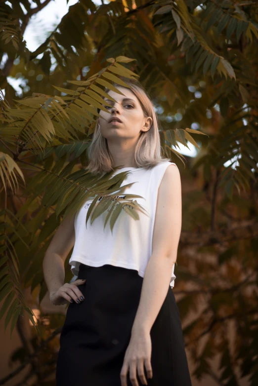 a woman is standing under a large plant