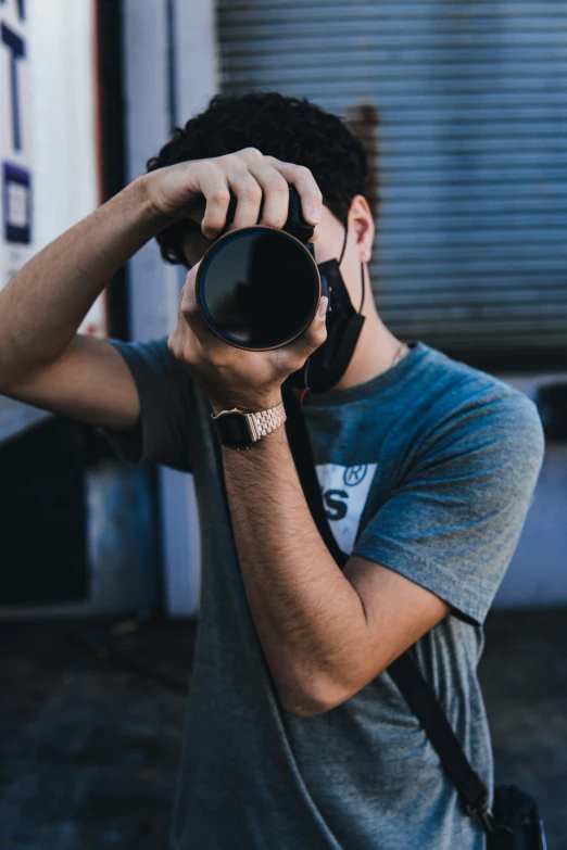 a young man is standing with his eyes closed looking through a camera