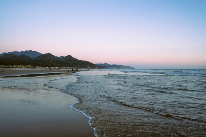 a beach with sand, water and mountains