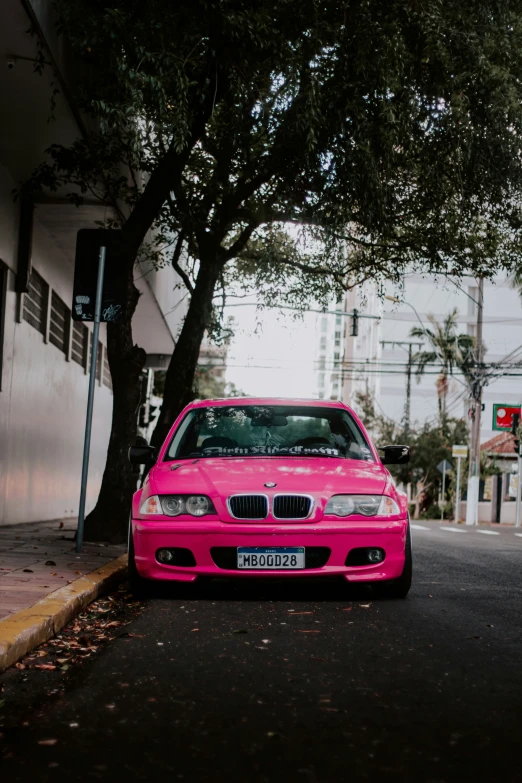 a bright pink car parked on the side of the road