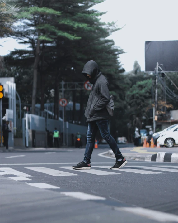 a person crossing a street wearing a hood