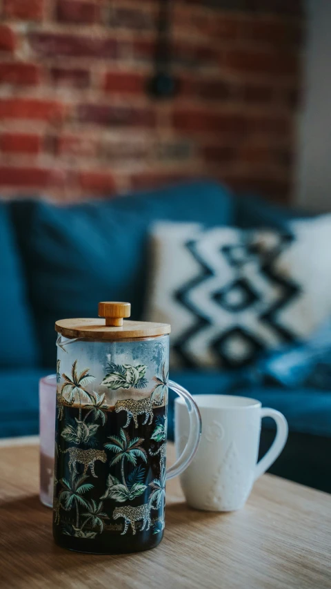 a clear, plastic cup with small plants on it sits next to a coffee mug