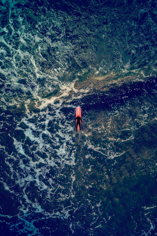 an overhead view of a person riding on a surfboard in the ocean