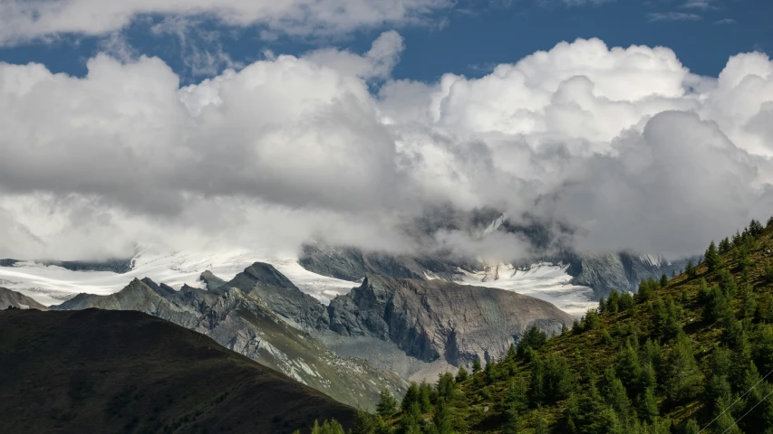 mountains with snow on them, and clouds hovering above